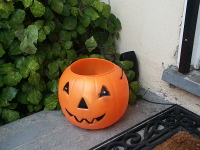 One speaker is hidden near a plant and behind a jack-o-lantern.
