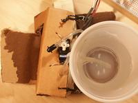 Top view of cup holding water, and pump tube attached to servo
